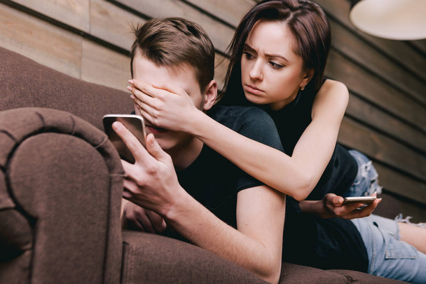 Young couple on sofa with cell phone - Фото, зображення
