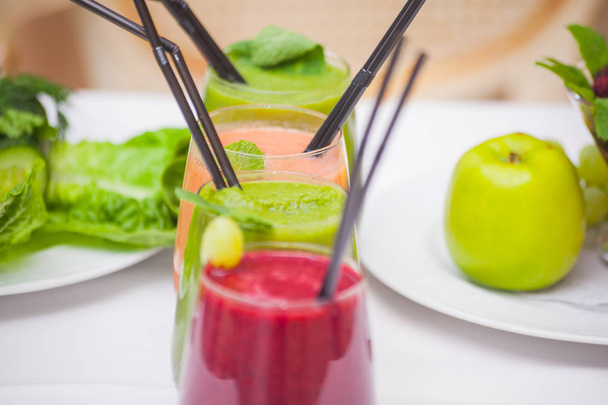 Red and green healthy smoothies with fresh ingredients on table. - Zdjęcie, obraz