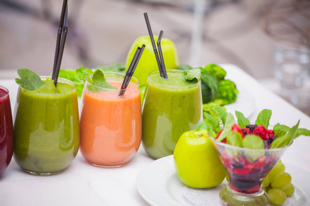 Red and green healthy smoothies with fresh ingredients on table. - 写真・画像