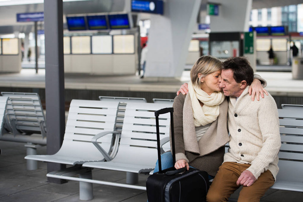 Senior couple waiting on train station, sitting on bench, kissin - 写真・画像