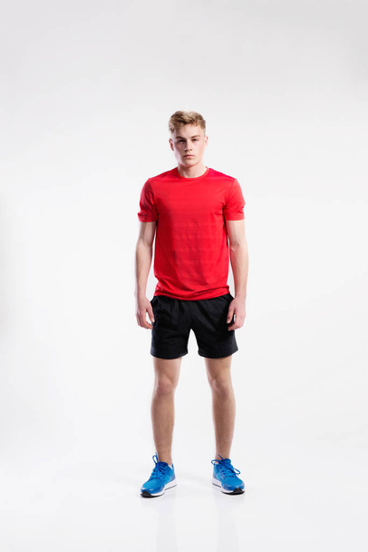 Handsome fitness man in red t-shirt and shorts, studio shot. - Foto, imagen