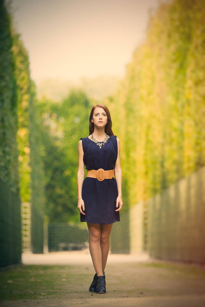красива молода жінка стоїть в парку повний кущів
 - Фото, зображення
