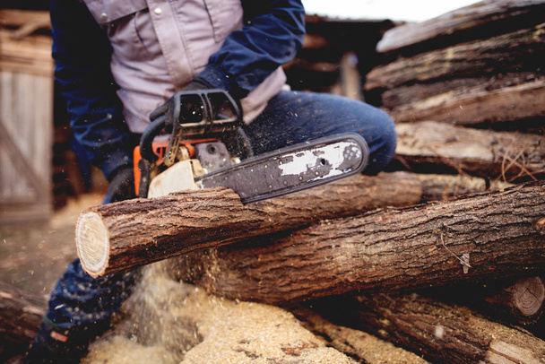 man die hout zaagt met kettingzaag - Foto, afbeelding