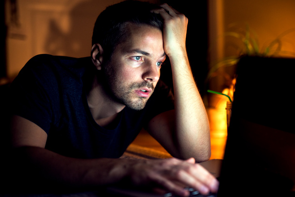 homem com laptop no quarto escuro
 - Foto, Imagem