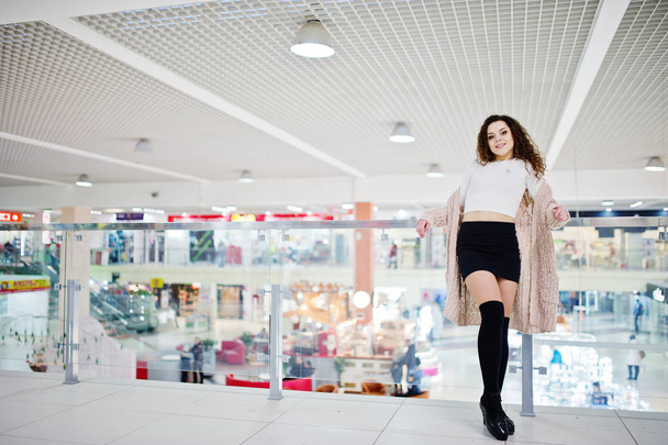 Young curly model girl posed on mini skirt at large shopping cen - 写真・画像