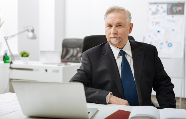 Serious aged businessman sitting in the office - Фото, зображення