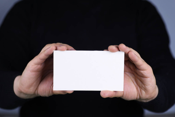 klein wit velletje papier in zijn hand man - Foto, afbeelding