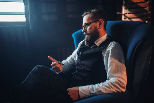  Сидящий в кресле бородатый мужчина
 - Фото, изображение