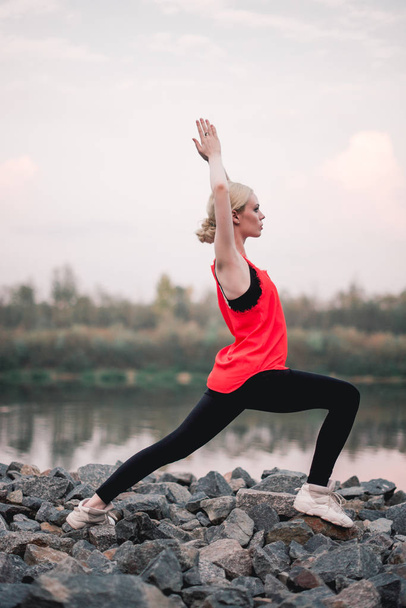 Chica joven haciendo ejercicio de yoga fitness al aire libre cerca del paisaje del río. Atardecer, Namaste Lotus pose. Meditación y Relajación
 - Foto, imagen