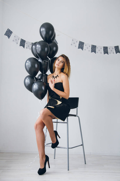Girl in a black dress with black balloons - Foto, imagen