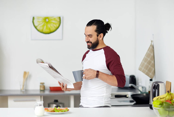man reading newspaper and eating at home kitchen - Foto, Imagen
