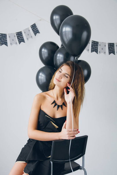 Girl in a black dress with black balloons - Fotó, kép
