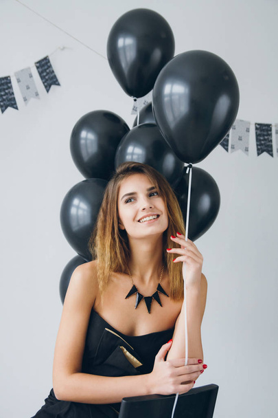 Girl in a black dress with black balloons - Φωτογραφία, εικόνα