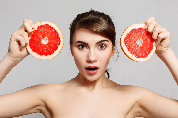 Beauty portrait of a happy woman holding grapefruit - Valokuva, kuva