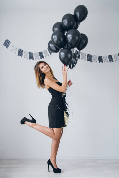 Girl in a black dress with black balloons - 写真・画像