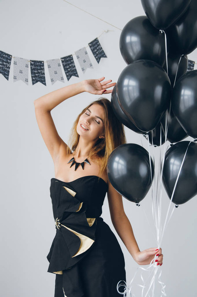 Girl in a black dress with black balloons - Foto, immagini