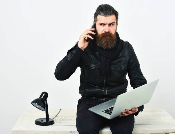 Bearded brutal caucasian hipster sitting on table with laptop - Foto, Imagen