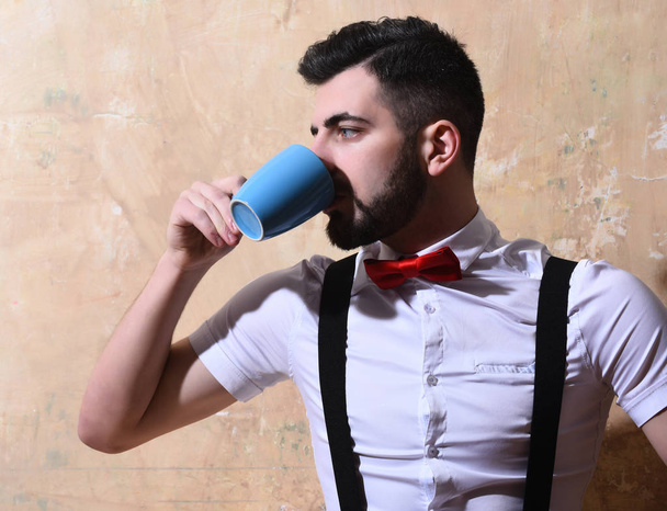 bearded man drinking coffee, tea from cup with serious face - Foto, Bild