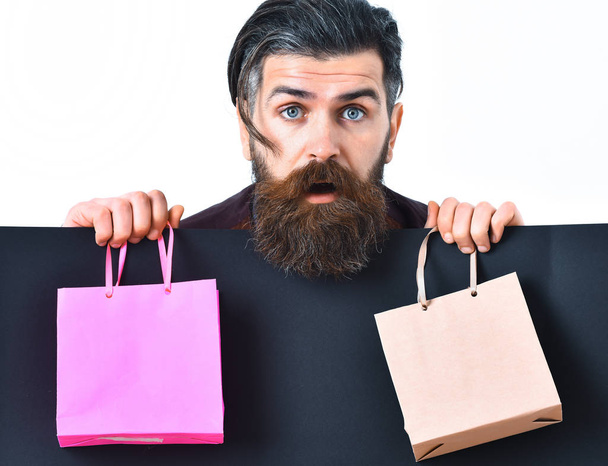 Bearded brutal caucasian hipster holding colorful package or bags - Foto, afbeelding