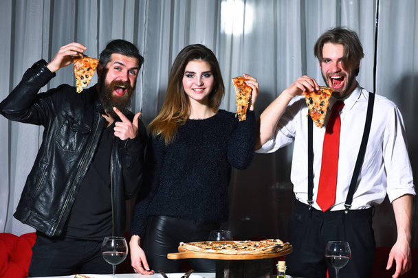 Happy friends eating tasty pizza slices with thumbs up gestures - Foto, Bild