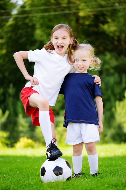 Two cute little sisters playing a soccer  - Fotoğraf, Görsel
