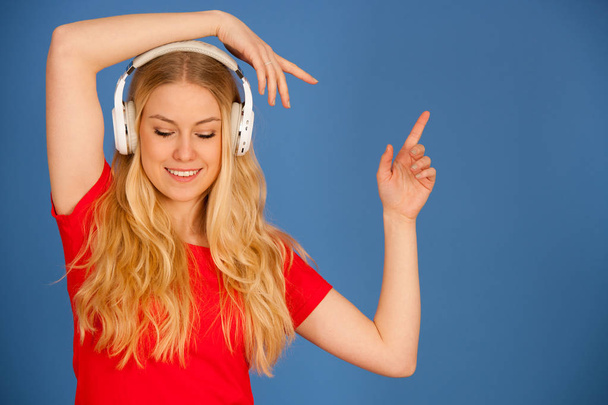 Young blonde woman with headphones  listens to the music over bl - Zdjęcie, obraz