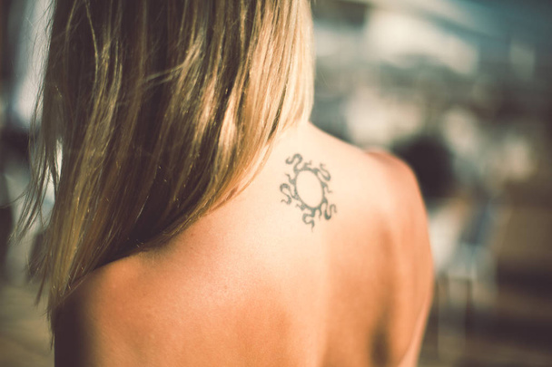 mujer bronceada con tatuaje en la espalda
 - Foto, Imagen