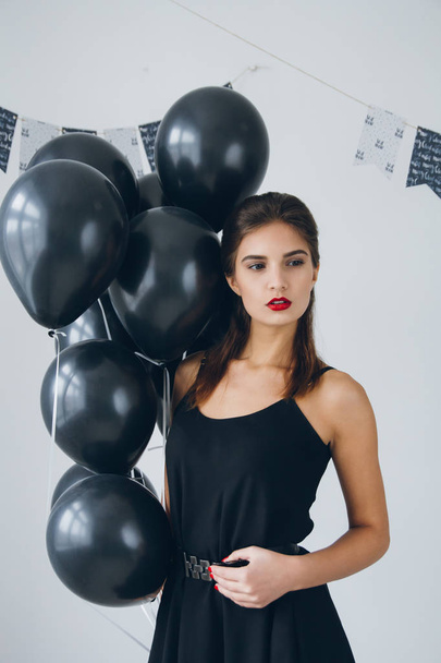 Girl in a black dress with black balloons - Foto, afbeelding
