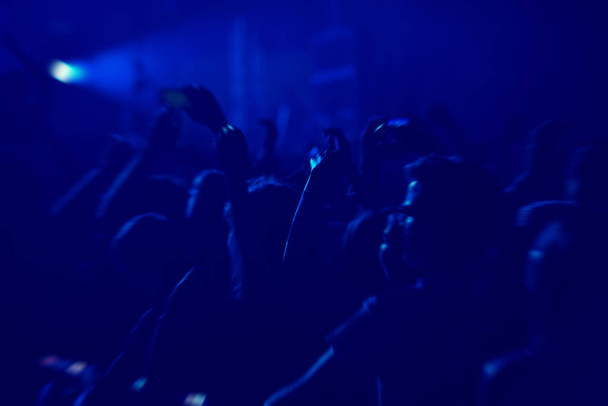 Πλήθος κουνιστό κατά τη διάρκεια μιας συναυλίας με υψωμένα χέρια. - Φωτογραφία, εικόνα