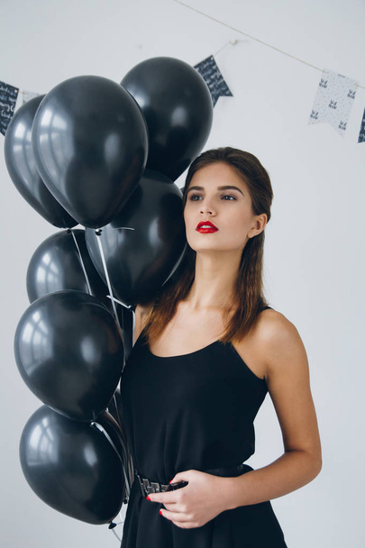 Girl in a black dress with black balloons - Foto, Imagen
