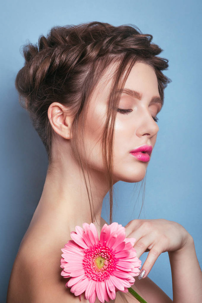 Portrait of romantic young woman with pink flower looking at camera on blue background .  Spring fashion photo. - Foto, Bild