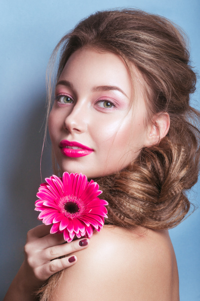 Πορτρέτο του ρομαντικά νεαρή γυναίκα με ροζ λουλούδι βλέπουν φωτογραφική μηχανή σε μπλε φόντο .   - Φωτογραφία, εικόνα
