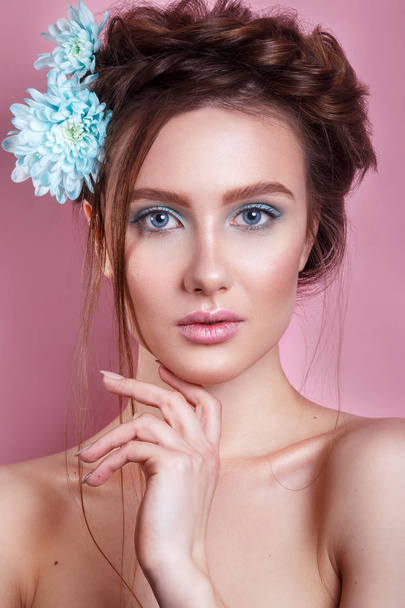 Portrait of romantic young woman with blue flower looking at camera on pink background.  Spring fashion photo. - Φωτογραφία, εικόνα