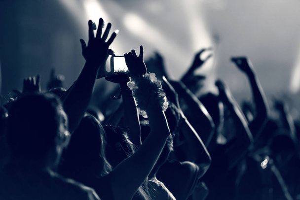 Толпа на музыкальном концерте, публика поднимает руки, тонизирует
 - Фото, изображение