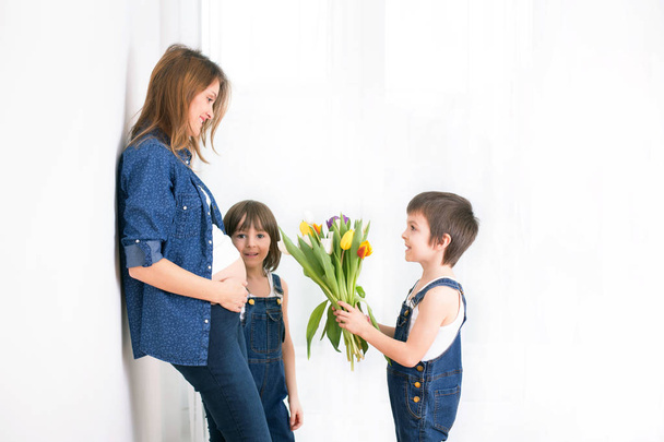Mãe grávida, abraçando seus filhos, recebendo tulipas, flores
 - Foto, Imagem