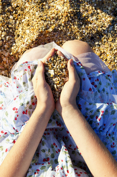 Girl's hands carrying sand and shells on the sand background - Photo, Image