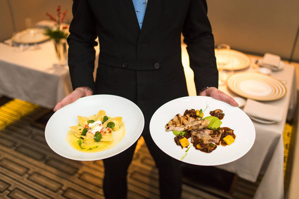 официант держит тарелки с едой
 - Фото, изображение