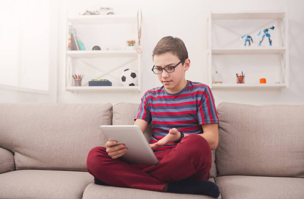 Tizenéves fiú segítségével digitális tábla kanapéval otthon - Fotó, kép