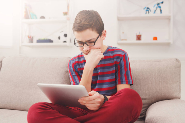 Teenage boy using digital tablet on couch at home - Photo, Image