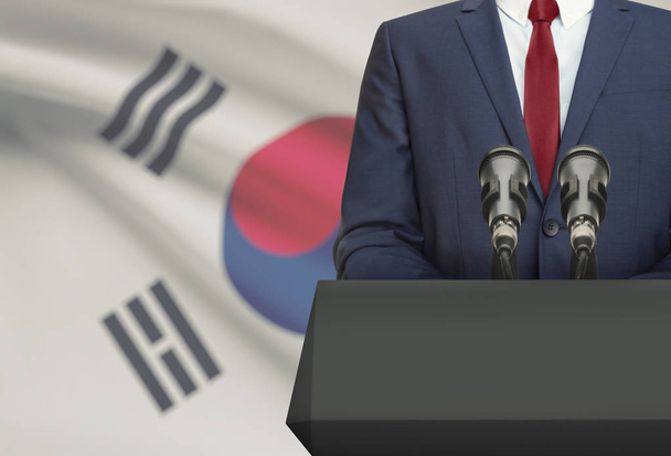 Επιχειρηματία ή πολιτικός κάνει ομιλία από πίσω από ένα άμβωνα με εθνική σημαία σε φόντο - Νότια Κορέα - Φωτογραφία, εικόνα