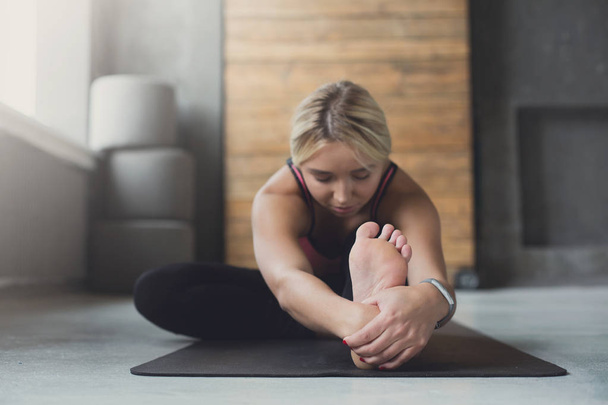 Woman makes yoga pose in class, sit forward bend asana - 写真・画像