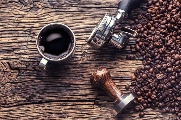 Caffè. Caffè nero con chicchi di caffè e portafiltro su vecchio tavolo in legno di quercia
 - Foto, immagini