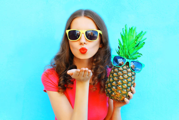 Fashion woman in sunglasses with pineapple sends an air kiss ove - Фото, изображение