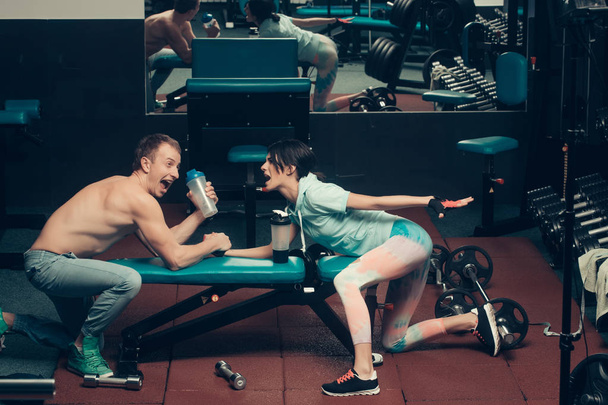 arm wrestling muscular man and girl at gym - Фото, изображение