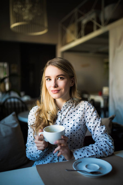 Young blond woman enjoying coffee time in cafe - Фото, изображение