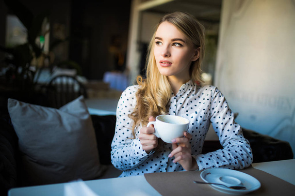 カフェでのコーヒー タイムを楽しむ若い金髪女性 - 写真・画像