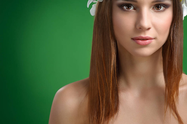 Young attractive woman with flowers in her hair posing in studio - Foto, afbeelding