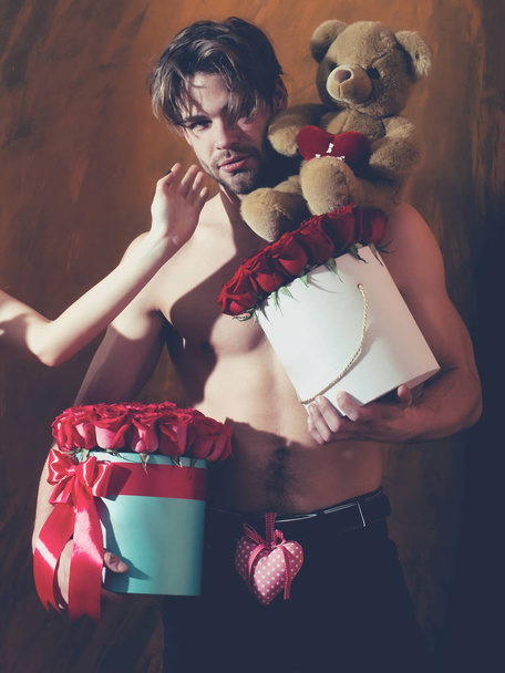 bearded muscular man with sexy body holds red rose box - Zdjęcie, obraz