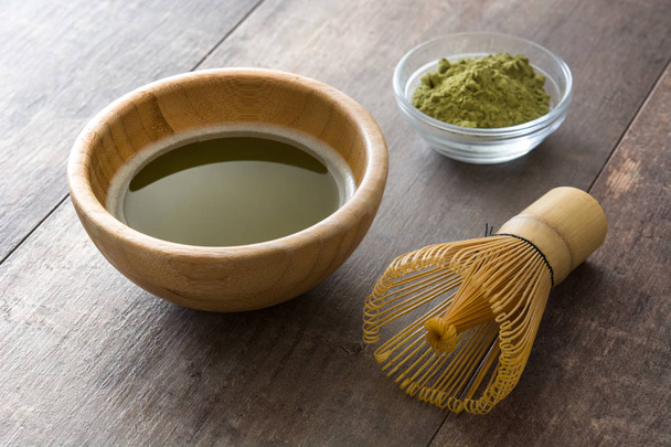 Зеленый чай маття в миске и бамбуковый венчик на деревянном столе
 - Фото, изображение