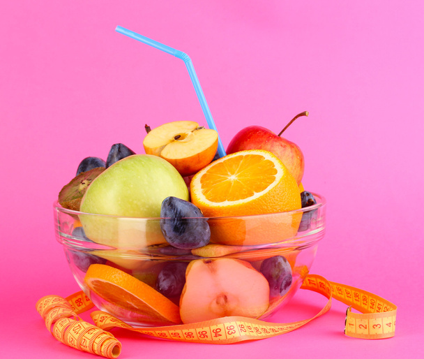 Glass bowl with fruit for diet and measuring tape on pink background - Fotografie, Obrázek